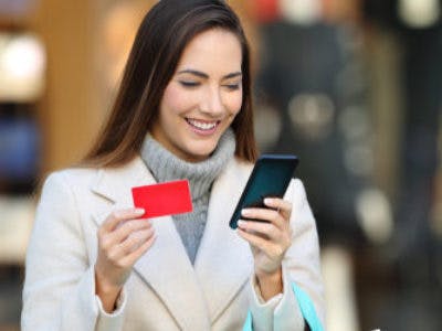 Female carrying NFC enabled gift card in hand looking at smartphone