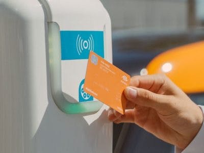 Hand holding EV charge RFID card against EV charger